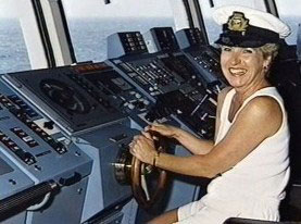 CarolLee Miles smiling at a ship’s helm